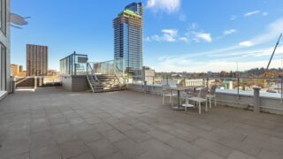 a brick walkway with a table and chairs and a building in the background